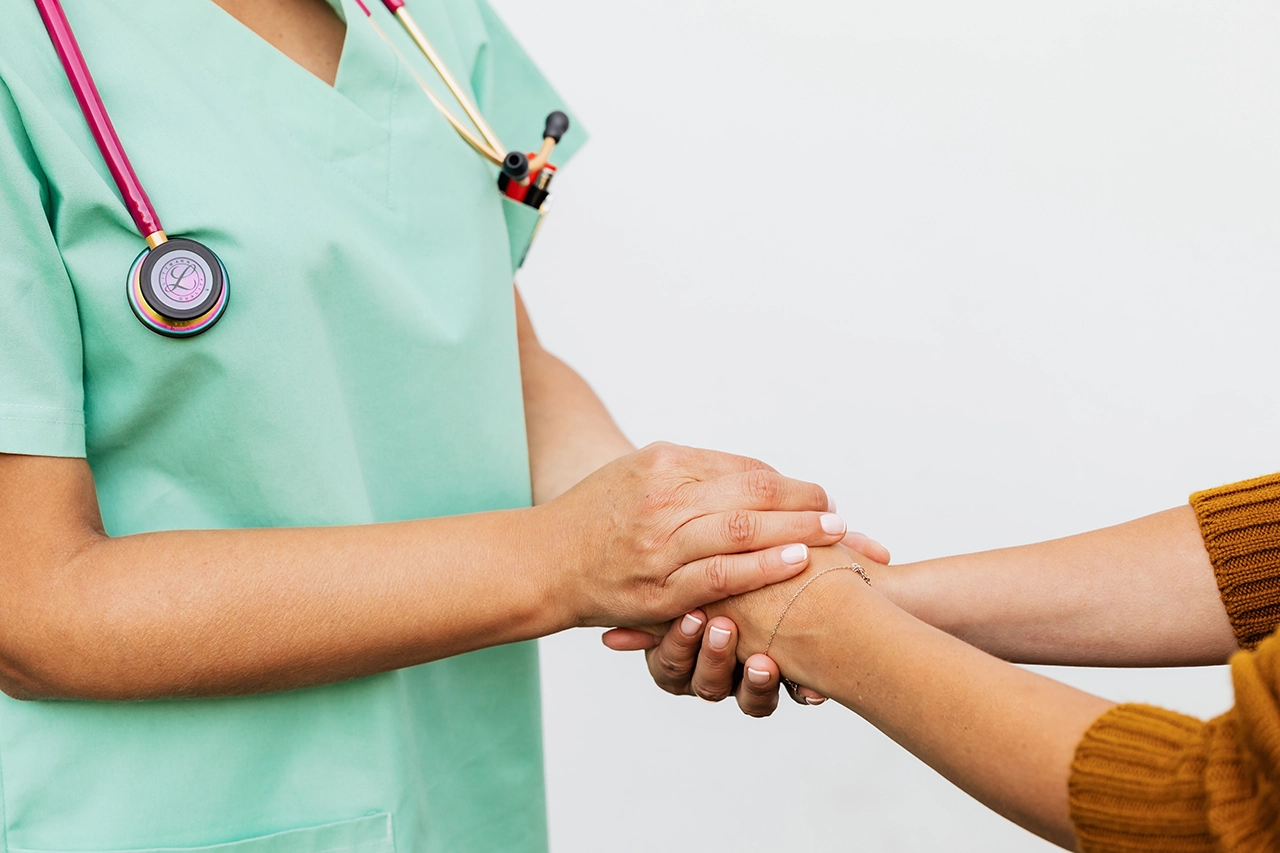 Profissional de saúde segurando as mãos de uma paciente com acolhimento